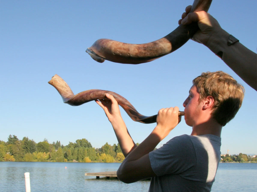A young man blows a shofar (a trumpet made from a rams horn), a cherished High Holy Days tradition.